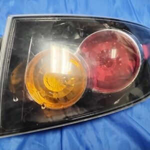 "Back housing view of 2004-2009 Mazda 3 Sedan passenger side outer tail light showing wiring sockets, mounting studs, and foam gasket"